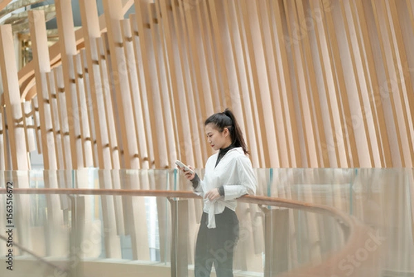 Obraz Beautiful woman leaning on railing using mobile phone