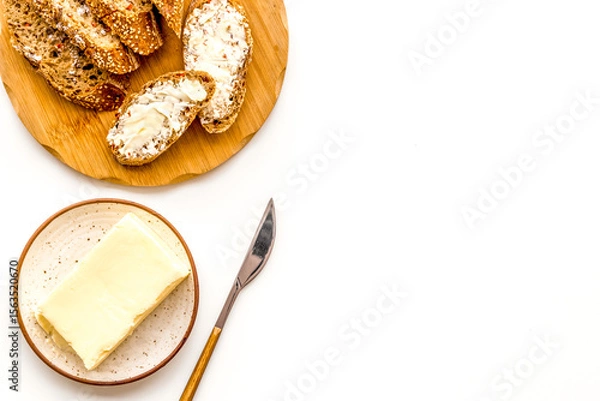 Obraz Slice of bread with butter on white background top view copy space