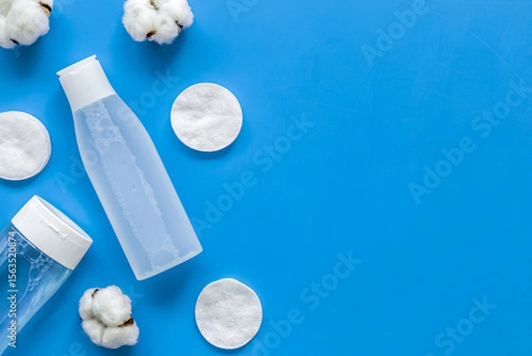 Obraz facial tonic, lotion and cotton pads for face care on blue background top view mock up