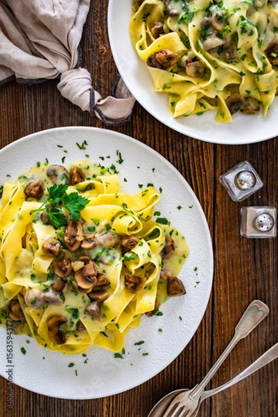 Fototapeta Papperdelle pasta with champignons mushrooms in cream sauce and parsley on wooden table