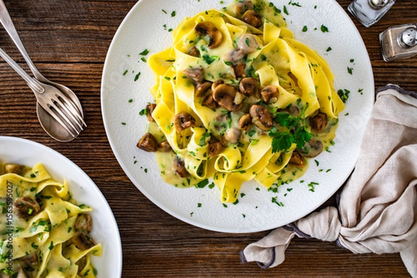 Fototapeta Papperdelle pasta with champignons mushrooms in cream sauce and parsley on wooden table