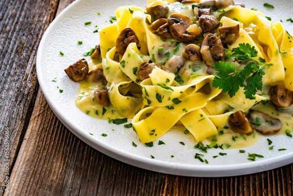 Fototapeta Papperdelle pasta with champignons mushrooms in cream sauce and parsley on wooden table