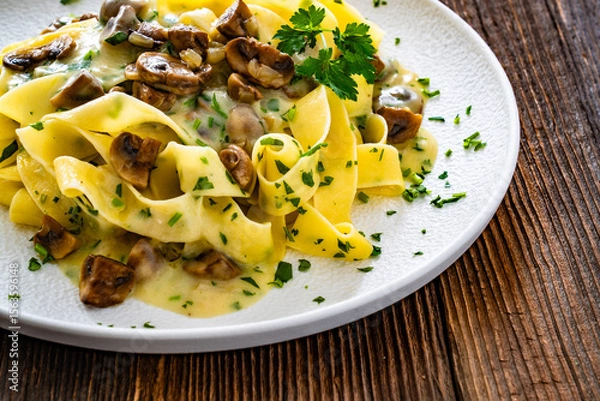 Fototapeta Papperdelle pasta with champignons mushrooms in cream sauce and parsley on wooden table