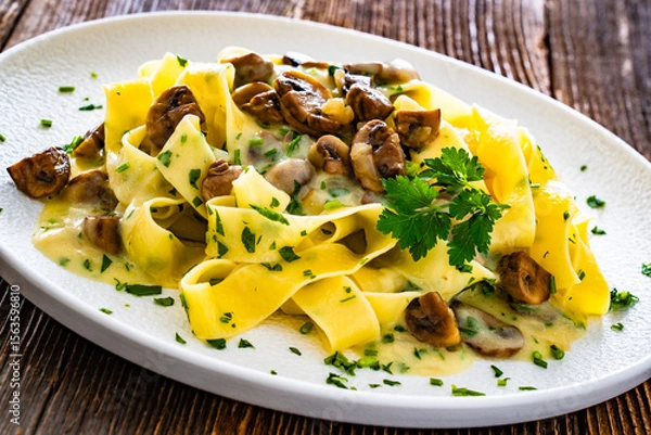 Fototapeta Papperdelle pasta with champignons mushrooms in cream sauce and parsley on wooden table
