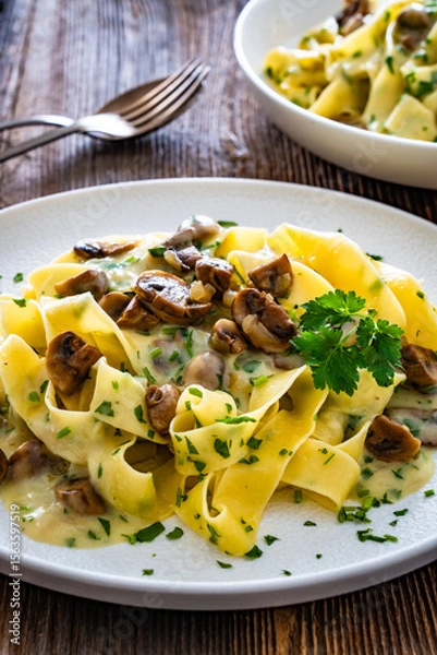 Fototapeta Papperdelle pasta with champignons mushrooms in cream sauce and parsley on wooden table