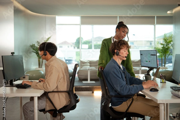 Fototapeta Team of tech customer support professionals working in modern office, wearing headsets and engaging with clients. environment is bright and collaborative, fostering productivity