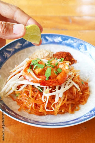 Obraz Squeezing Lime Juice into Freshly Cooked Pad Thai Noodle for Adding Tartness