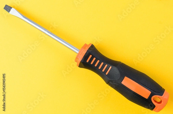 Fototapeta Flathead screwdriver single metal hand tool isolated on bright yellow background top view