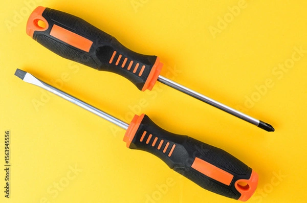 Fototapeta Phillips and flathead screwdrivers metal hand tools on bright yellow background top view