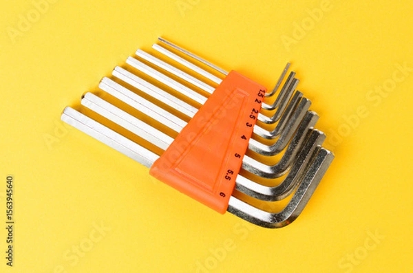 Fototapeta Set of hex keys arranged on bright yellow background metal allen wrenches top view