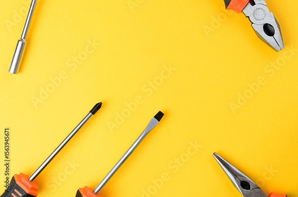Fototapeta Empty center space with screwdriver flathead philips pliers on both sides yellow background