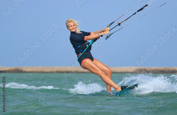 Fototapeta Kite surfing dziewczyna w seksownym stroju kąpielowym z latawcem na niebie na kiteboard na falach błękitnego morza, mówiąc cześć. Aktywność rekreacyjna, sporty wodne, akcja, hobby i zabawa latem. Sport kiteboardingowy