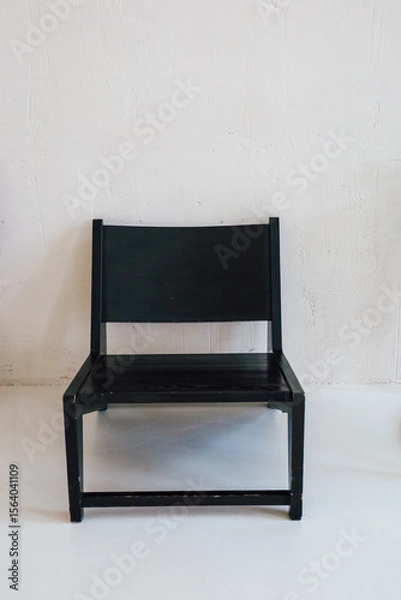 Obraz Modern black chair stands alone against a minimalist white backdrop in a bright room