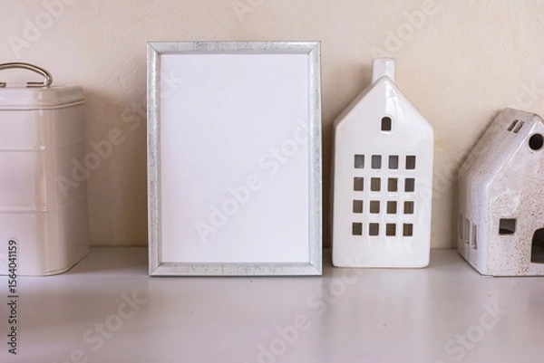 Obraz Blank picture mockup frame and decorative ceramic houses on a wooden table