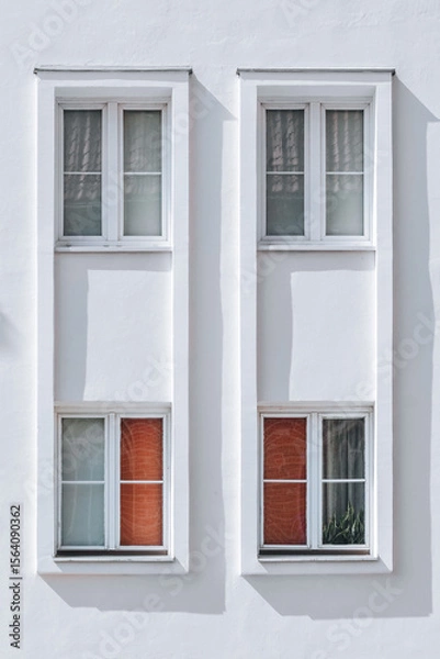 Fototapeta White Minimalist Facade with Four Symmetrical Windows and Red Blinds