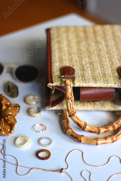 Obraz Wicker purse, sunglasses, scrunchie, lipstick and various gold and neutral jewelry on white background. Selective focus.