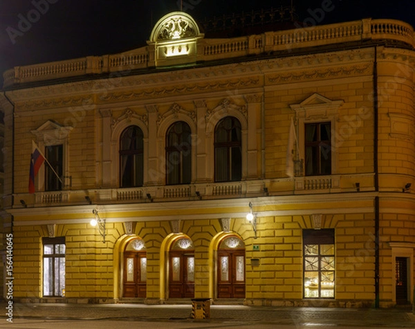 Fototapeta Illuminated historic building in Ljubljana at night with classical facade