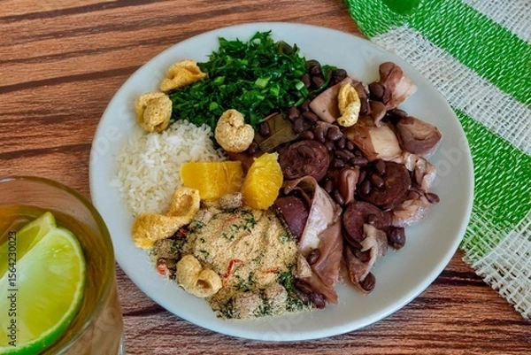 Fototapeta The best traditional Brazilian feijoada completely served in the most authentic style accompanied by the irresistible and iconic cachaça caipirinha