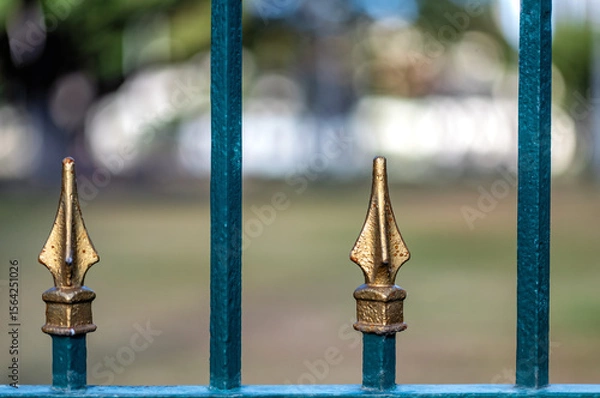 Fototapeta Closeup of a Ceremonial Teal and Gold Fence with Points Against a Blurred Background.
