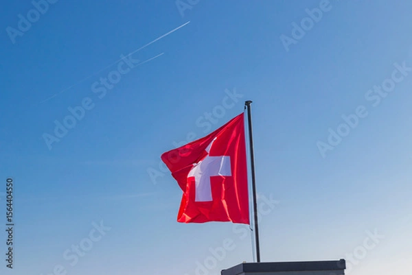 Obraz Red Swiss flag over the blue sky background