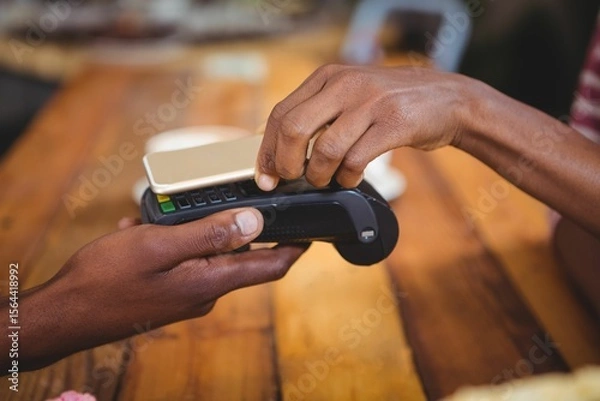 Obraz Woman paying bill through smartphone using NFC technology in cafe