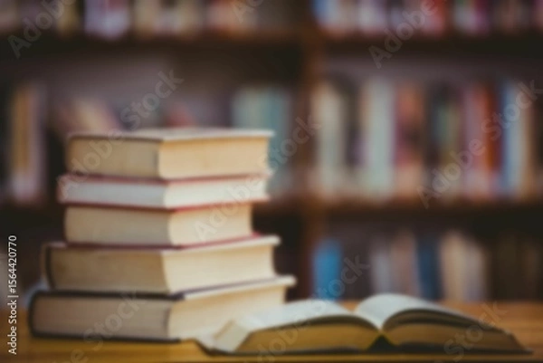 Obraz flat design is showing stack of hardcover books, open book on wooden table before blurred bookshelf