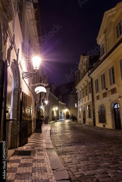 Fototapeta Flat style cobblestone street is glowing at night, featuring lanterns, shutters and signage bracket