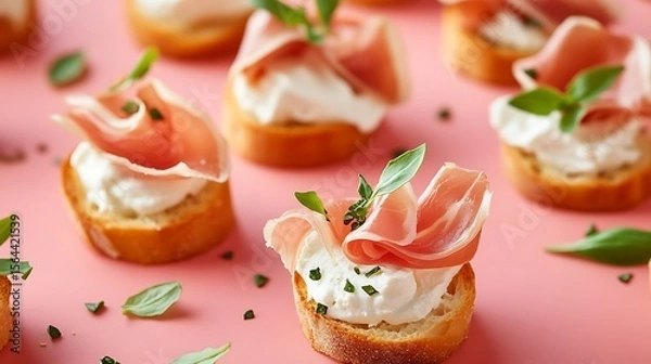 Obraz Prosciutto appetizer bites with creamy cheese and fresh basil on a vibrant pink surface, perfect for parties and culinary creations.