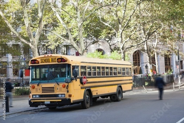 Fototapeta Yellow school bus is parked in flat design along street under leafy trees, showcasing iron fence