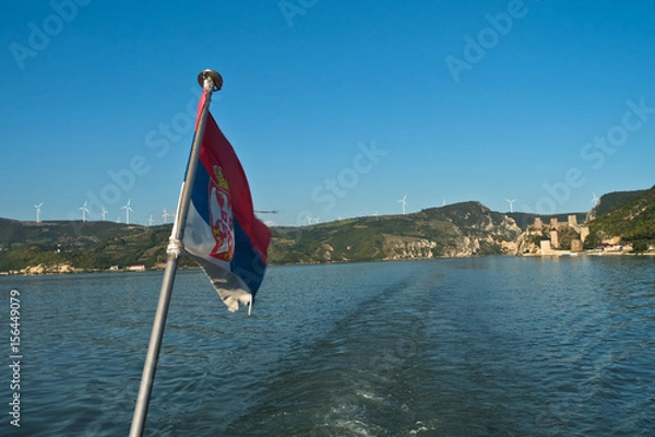 Fototapeta Cruiser ship sales on Danube river at sunny summer day with Golubac fortress in background, Serbia