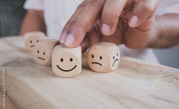 Obraz Hand holding wood cube with smile icon, World mental health day or feedback rating concept, Positive customer review, Wood cube stacking with emotion face icon on wood background