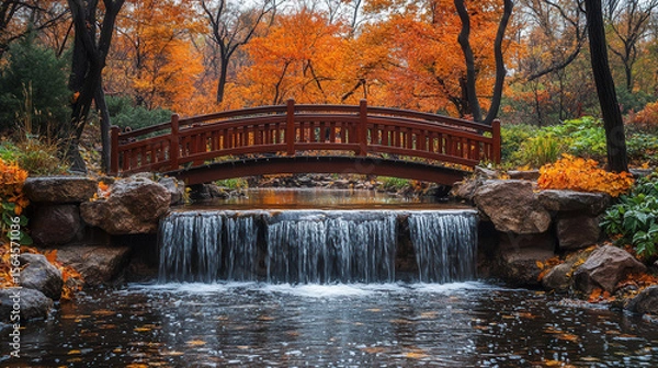 Fototapeta hidden waterfall flowing through autumn woodland with rustic wooden bridge and vivid fall foliage
