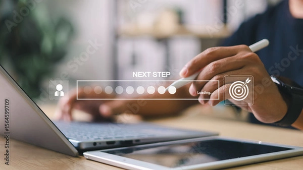 Fototapeta Businessman interacting with digital progress bar and “Next Step” interface on laptop and tablet. Concept of business development, decision making, and digital process.