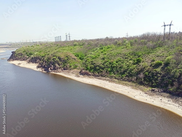 Fototapeta View from the Arch Bridge on the calm water surface of the Dnieper that washes the sandy shores and rocky cliffs of Khortytsia Island.