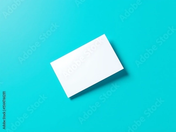 Fototapeta A clean white rectangular card is placed diagonally on a bright turquoise blue background with a subtle shadow