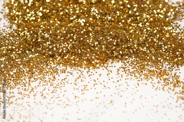 Obraz A sparkling close-up of loose gold glitter, piled at the top and scattered across a light surface, creating a festive background