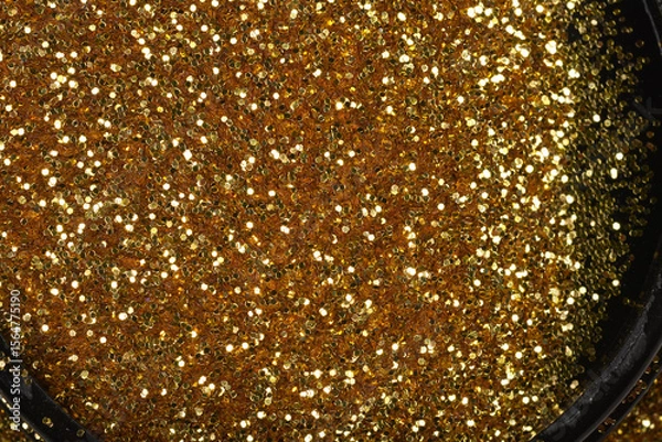 Obraz A close-up, high-angle view of dense gold glitter contained within a black, curved edge, creating a vibrant, sparkling texture