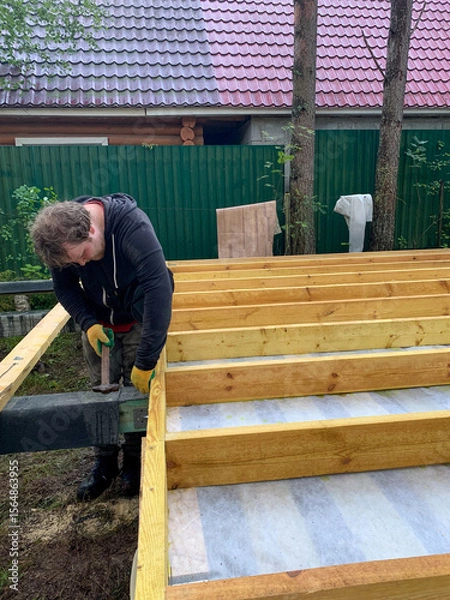 Fototapeta A determined Caucasian man diligently works on a treehouse, echoing DIY craftsmanship and International Woodworkers' Day spirit