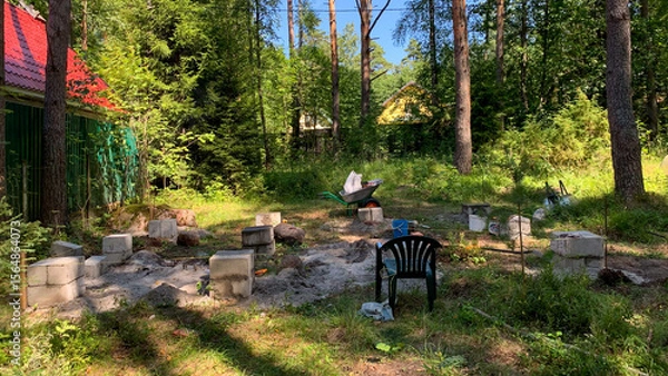 Fototapeta Sun-dappled clearing with empty chairs around a makeshift fire pit, echoing Midsummer folklore and secret garden gatherings