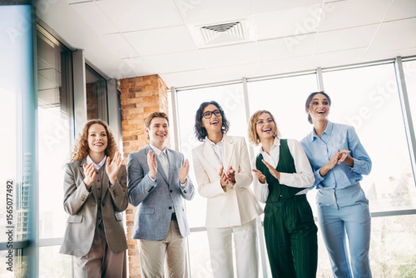 Fototapeta Group of professional coworkers applauding during a team meeting in a modern office space, celebrating success