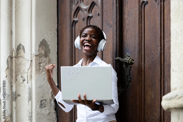 Obraz Portrait of happy black African student holding laptop and studying at the college.
