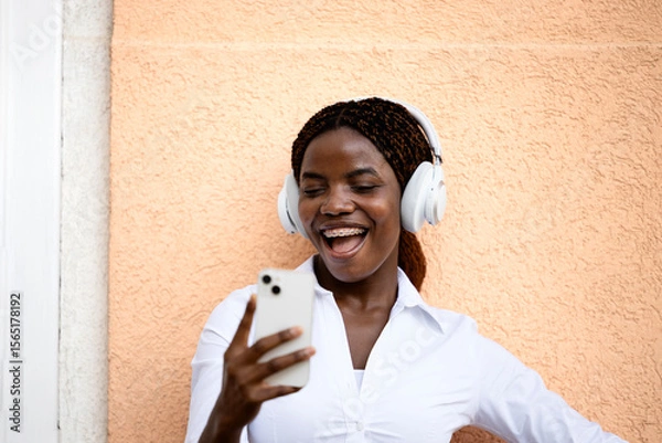 Obraz Happy smiling African woman using smart phone and laughing.