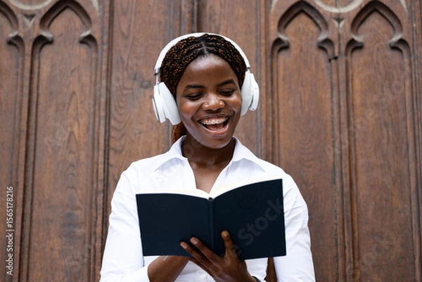 Obraz Portrait of happy black African student holding book and studying at the college.