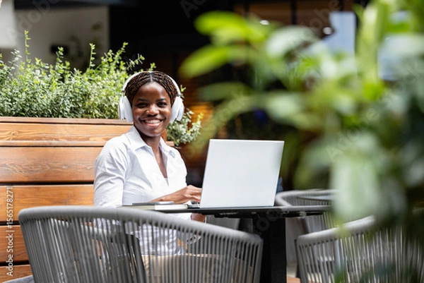 Obraz Portrait of elegant black African woman in business suit working on laptop computer in cafe bar.