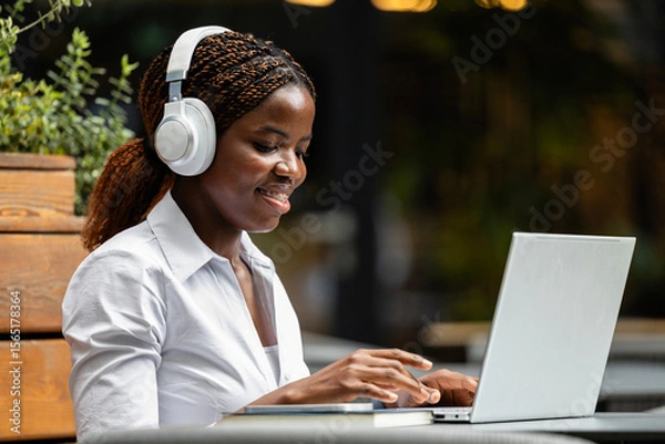 Obraz Elegant black African woman in business suit working on laptop computer in cafe bar.