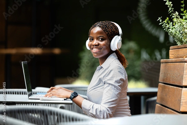 Obraz Elegant black African woman in business suit working on laptop computer in cafe bar.