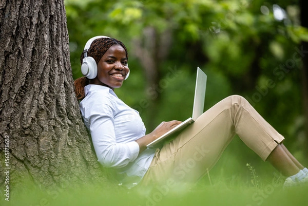 Obraz African American female student with laptop computer studying in the park and enjoying nature.