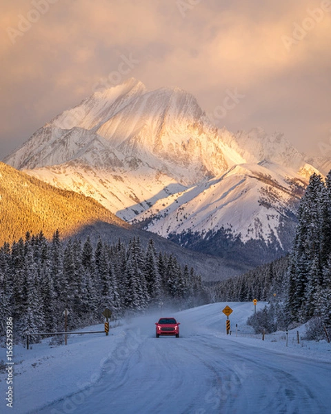 Obraz Red car driving on snowy road at sunrise in Kananaskis Country