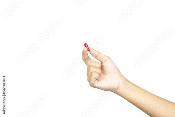 Fototapeta A female hand holding up a red medicine capsule or pill. Concept of choice and health treatment, isolated on white background with clipping path.