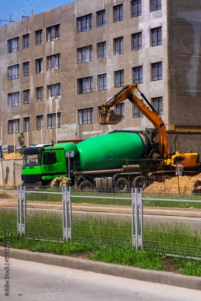 Fototapeta A large green concrete mixer truck is being loaded with fresh concrete